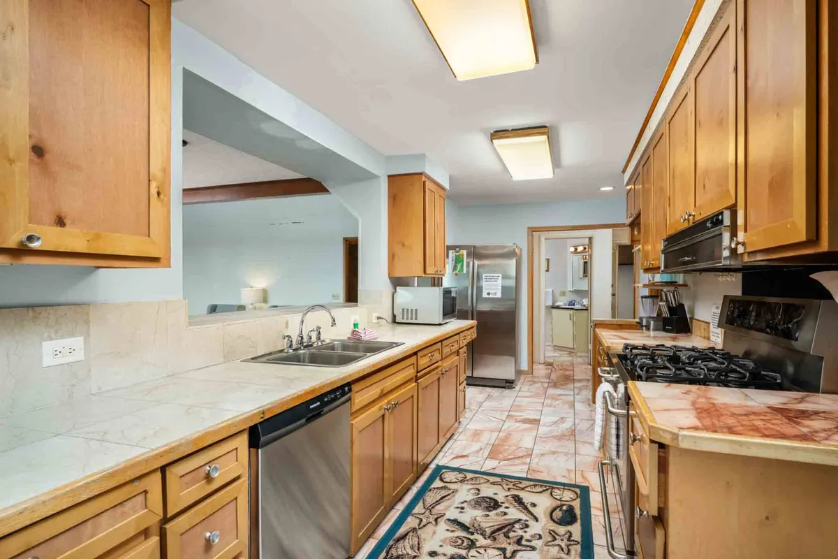 A modern kitchen with a clean countertop, stainless steel appliances, and wooden cabinetry. The space is open and inviting, seamlessly connected to the living and dining areas, ideal for cooking and entertaining while staying part of the gathering.