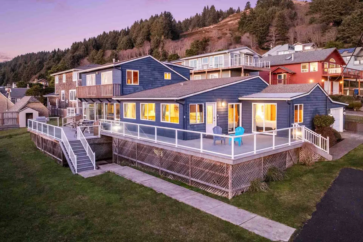 This image shows a spacious deck furnished with chairs, overlooking a lush, green lawn. Large windows from the house open onto the deck, blending indoor and outdoor spaces. The green lawn in the foreground is well-maintained and inviting.