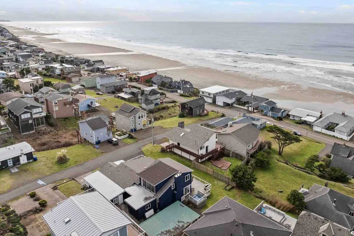 This view captures beachfront houses lined along a coastal road, with ocean waves rolling in nearby. The open environment is inviting for walks and outdoor activities, connecting the property to the beach.
